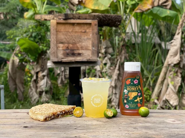 Wildflower honey drink, honeycomb, hive box, and honey bottle on a wooden table