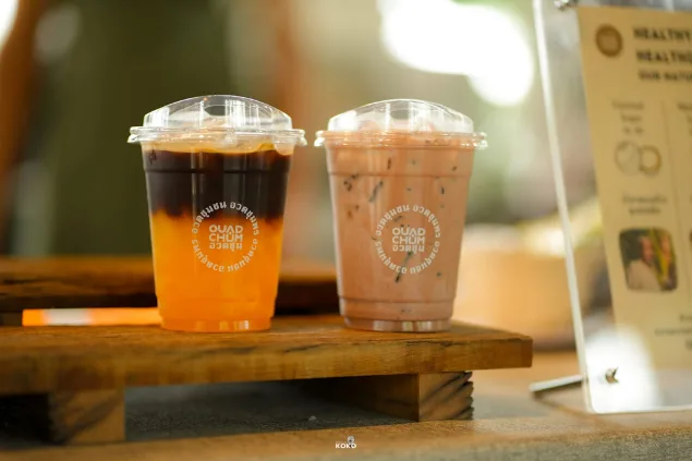 Two iced Baan OuadChum coffee drinks on a wooden tray