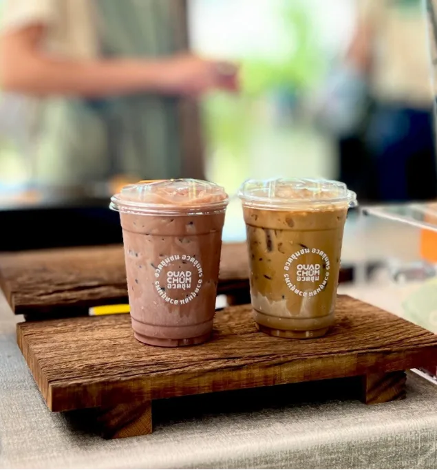 Two iced coffee drinks served on a wooden board outdoors