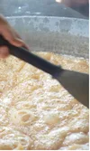 Nipa palm syrup being slow-stirred as it cooks down in the pan